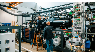 To medarbejdere står i HTHP Lab og justerer på en del af rørene